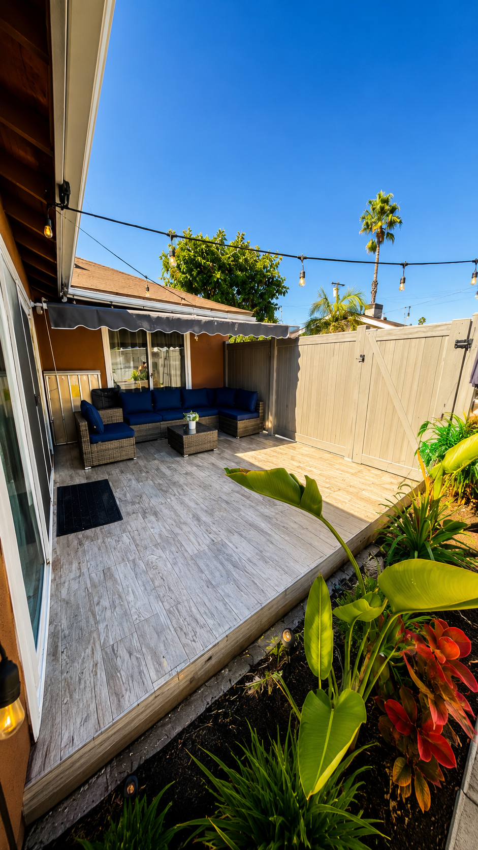 Outdoor patio with shaded wicker lounge seating and a private fenced yard